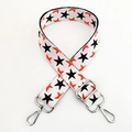 Close-up of a wide woven strap with orange birds and black stars pattern and silver hooks - White Base Black Star Silver Buckle