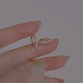 Elegante gouden parel oorbellen met kleine witte parels getoond op een hand voor schaal - Goud