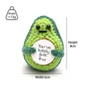 Macro shot of handmade crochet avocado doll with a positive message card and soft texture - Christmas Green Avocado