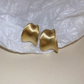 Macro shot of abstract curved golden earrings with a brushed metal texture on soft fabric - Gold Twisted C-Shape (925 Silver Needle)