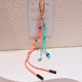 Détail du porte-clés tressé rose et turquoise avec fermoir doré et breloque fleur - 51.A08 Pendentif Fleur Orange Rose Vert