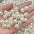 Hand holding high-lustre white round faux pearls with golden metal loop caps - 4mm Pearl Eye Pin Pendant / Cream Pearl KC Gold Eye Pin
