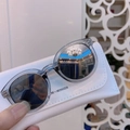 Close-up of kids' gray-blue sunglasses with a textured white leather case and dark lenses - Transparent Grey Frame Silver Mirror Lens