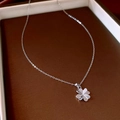 Primo piano di una collana con ciondolo a quadrifoglio argento su vassoio scuro - Argento