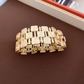 Dettaglio del bracciale rigido dorato largo con trama a spirale su un tessuto marrone - Stile Quadrato a Spirale Dorata