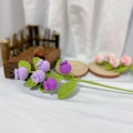 Macro detail of hand-knitted purple crochet flowers with green leaves on white fabric - Purple Blueberry