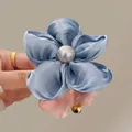 Blue satin flower hair clip with a grey pearl center held in hand for elegant styling - Blue Flower Scrunchie