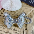 Goldener Schmetterling Haarklammer mit Zirkonia und Kristallen auf weichem weißem Hintergrund - Zirkonia Schleife Pferdeschwanz Clip