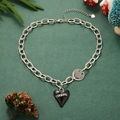 Detail of silver link chain necklace with black heart and smiley face charms on green background - Silver Smiley Face With Black Heart
