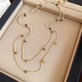 Dettaglio di una collana di perle occhio di tigre e cristallo su un portagioie beige - Collana-Bianco-Occhio di Tigre