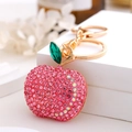 Close-up of pink rhinestone apple keychain with gold chain and green leaf charm - Pink Rhinestone Apple