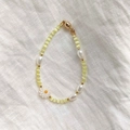 Detail view of yellow cat eye beads and white daisy charm on a gold-plated clasp necklace - Yellow Cat's Eye Daisy Bracelet 18cm