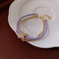 Detalle de pulsera de cuero púrpura con cadena dorada y hebilla de circonita en forma de X - Pulsera-Púrpura