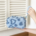 Blue plush heart patterned makeup bag with top handle shown in a soft lifestyle setting - Handheld Plush Blue Heart