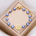 Bracciale dorato con tredici perline occhio blu e ciondolo centrale rotondo - Lettera O