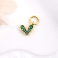 Macro shot of heart-shaped gold charm with green cubic zirconia on white background - Green