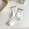 White ribbed Lolita socks with black wave edge and pink bow accent on a clean table - White Base Pink Bow