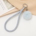 Détail du porte-clés pompon bleu clair avec corde tressée scintillante et fermoir en métal - Bleu clair