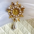 Close-up of vintage matte gold brooch featuring pearl leaves and a queen portrait coin - Vintage Coin Leaf Style