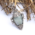 Macro shot of vintage copper bottle pendant with grey-green gemstone and star detail - Labradorite
