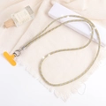 Dettaglio della catena per telefono con strass e chiusura in metallo su tessuto bianco - Cordino a Catena in Strass / Giallo (K1140)
