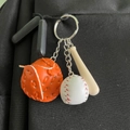 Miniature baseball keychain with orange glove, white ball, and wooden bat on black bag - Small Baseball Glove and Bat Set / Orange