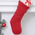 Classic red cable knit Christmas stocking with a gift box hung on a white fireplace mantle - Red
