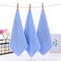Three light blue coral fleece square towels hanging on a rope with wooden clips - 23x23cm / Blue
