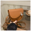 Close-up of brown saddle bag with silver oval metal buckle and adjustable shoulder strap - Brown