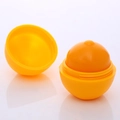 Κοντινό πλάνο ενός lip balm σε σχήμα πορτοκαλιού με ρεαλιστική υφή και κίτρινο βάλσαμο - Λεμόνι
