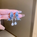 Blue crystal butterfly earrings with drop pearl pendants on silver needles in hand - Blue Butterfly Pearl Drop