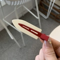 Retro cream and deep red metal hair clip shown in a hand-held view for daily hair styling - Off-white & Red