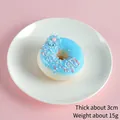 Himmelblauer künstlicher Donut mit rosa Glasur und blauer Blume auf weißem Teller - Azurblau (Perlen-Donut)