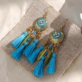 Bohemian dangle earrings with blue tassels and golden floral discs on burlap background - Sky Blue Antique Gold Tassel Style
