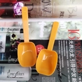 Close-up of two bright orange long-handle plastic measuring spoons for milk powder - Orange