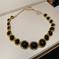 Detailed macro view of the gold necklace featuring large black resin round pendants - Necklace-Gold-Black