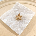 Golden starfish hair clip with central white pearl and detailed textured surface finish - Starfish