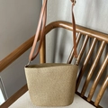 Handwoven straw shoulder bag in beige with adjustable brown leather strap on chair - Brown