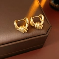 Detailansicht der eleganten goldenen Knotenohrringe auf einer braunen Schmuckschatulle - Gold