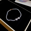 Close-up of a sparkling zircon bow pendant bracelet displayed in a velvet jewelry box - Silver