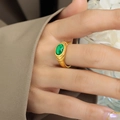 Retro gold titanium steel ring featuring an oval green glass stone on a finger - Ring / Gold & Green Crystal / US 6