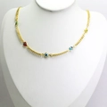 Close-up of golden necklace with colorful evil eye charms on a jewelry display - Colorful