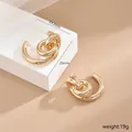 Detailansicht der unregelmäßigen goldfarbenen Tropfenohrringe mit hohlem Twist-Design und 25mm - Gold Multi-Ring