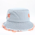 Dettaglio di un cappello a secchiello in denim blu con fori arancioni e bordi sfrangiati - Arancione