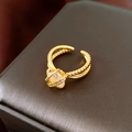 Primer plano de un anillo dorado trenzado con circonita sobre estuche de cuero - Estilo Abierto de Cuerda Trenzada (WR510) / Dorado