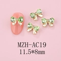Macro detail of gold bow nail charms with green rhinestones sized 11.5x8mm on pink base - Gold Base Green (AC19)