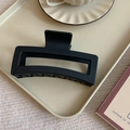 Detalle de una pinza de pelo cuadrada negra mate en un plato decorativo beige con lunares - Negro mate