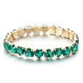 Detail view of heart-cut emerald green crystals set in a golden claw setting bracelet - Emerald