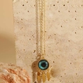 Detailed view of evil eye pendant with gold leaves on a natural stone background - Black Leaf