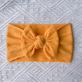 Detailed close-up of bright yellow ribbed knit baby headband with a large bow detail - Yellow